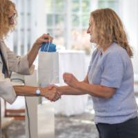 faculty shaking hands and handing out bag